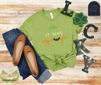 St. Patrick's Day shirt with the word "Irish" in green and a clover for the "I" dot, the words "it was" in white all uppercase, and "Halloween" in orange with a bat in place of the "w" and orange blood drips off two letters, in heather green.