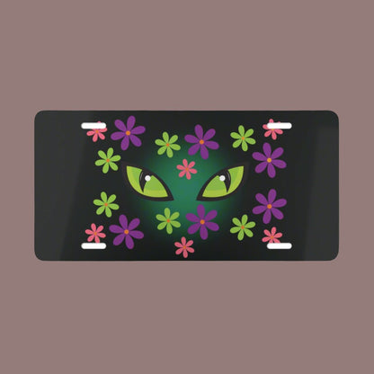 Cat Halloween vanity plate with spooky green cat eyes in the middle of purple, pink and green flowers, with a blue glow behind them, black background.