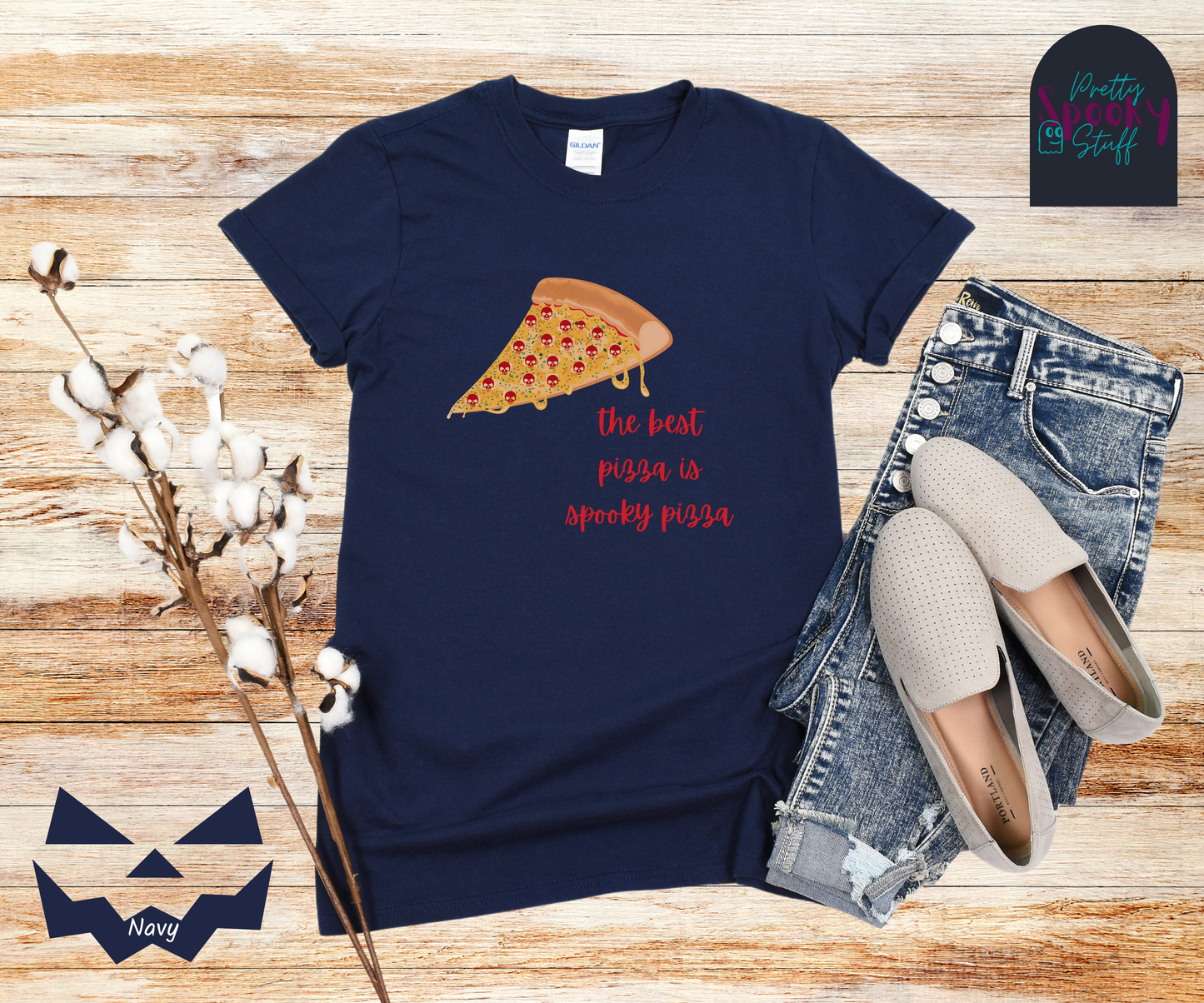 Pizza shirt with a slice of pepperoni pizza with skull shaped pepperonis and the words "the best pizza is spooky pizza" in red cursive font, in navy