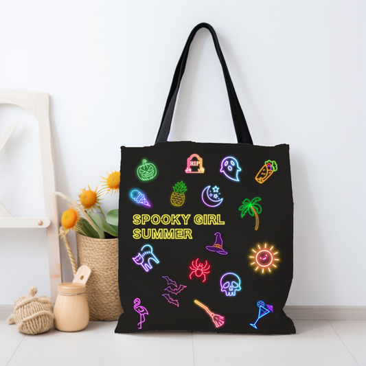 Spooky Girl Summer tote bag featuring a mix of spooky and summer themed neon icons with the with the words "spooky girl summer" in neon yellow letters in the middle, black fabric and handle.