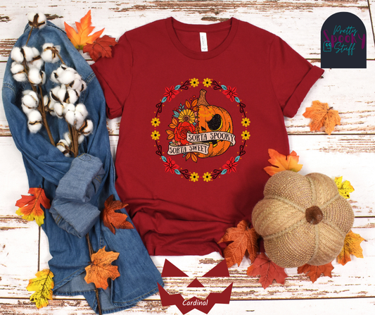 Pumpkin Halloween shirt with a circle of yellow, red, and blue flowers, surrounding a half jack o' lantern half floral design with the words "sorta sweet sorta spooky" on banners, in cardinal