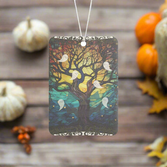 Halloween ghosts air freshener with stained glass design featuring a sprawling bare tree reaching upwards and ghosts flying all around, hanging with a fall background.