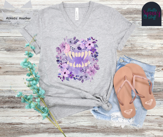 Spooky girl summer v-neck tee featuring florals in shades of purple, with a set of vampire teeth in the middle, with a pink butterfly in a subtle perch on a fang, in athletic heather. 