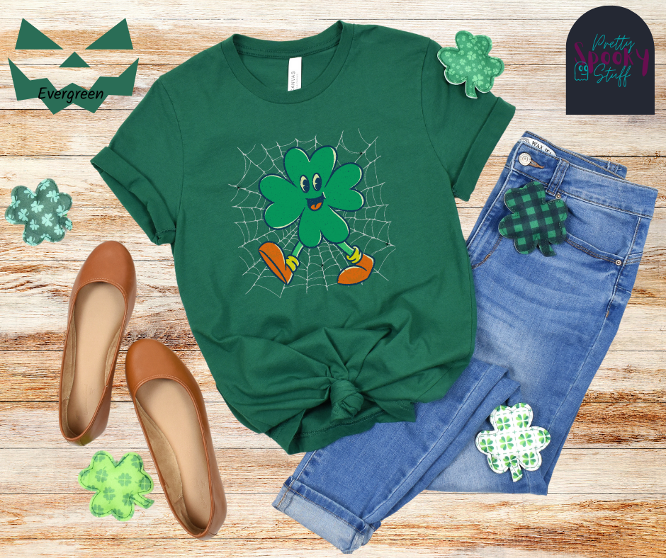 St. Patrick's Day shirt with four-leaf clover character on a spiderweb background with small spiders around it, in evergreen.